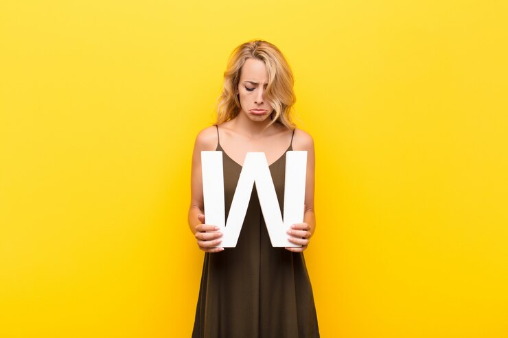 Foto traurig, depressiv, unglücklich, hält den buchstaben w des alphabets, um ein wort oder einen satz zu bilden.