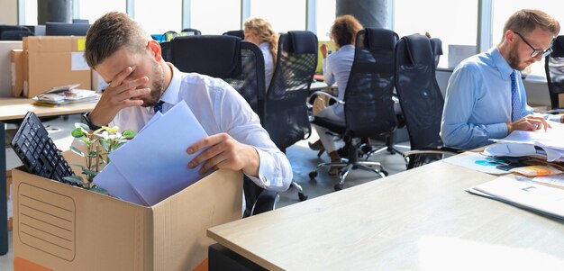 Foto traurig entlassener arbeiter nimmt seine büromaterialien mit aus dem büro