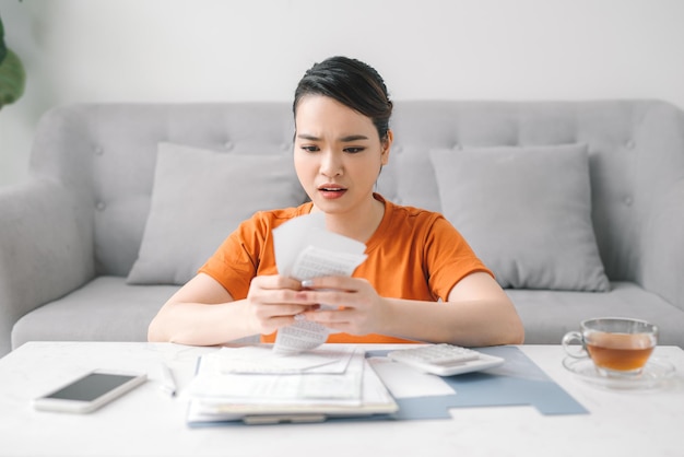 Traurige Asiatin in finanziellen Schwierigkeiten im Wohnzimmer