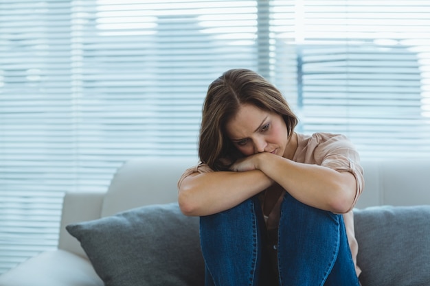 Traurige Frau, die auf Sofa sitzt