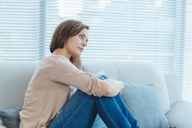 Traurige Frau, die auf Sofa sitzt