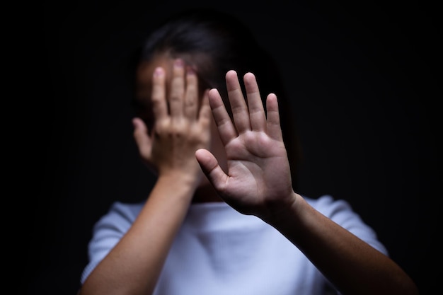 Foto traurige frau, die ihr gesicht mit der hand vor schwarzem hintergrund bedeckt