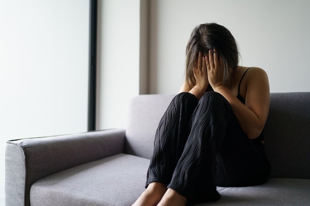 Traurige Frau, die über Probleme nachdenkt, auf einem Sofa sitzt, verärgert Mädchen, das sich einsam und traurig fühlt wegen einer schlechten Beziehung oder depressiver Frau, Störung der psychischen Gesundheit