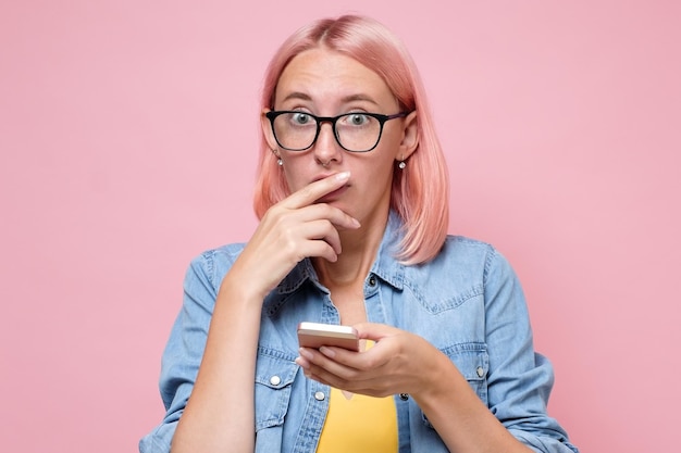 Foto traurige frau mit gefärbten rosa haaren, die auf ihr handy schaut