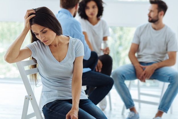 Traurige freudlose junge Frau, die ihren Kopf hält und sich verzweifelt fühlt, ohne zu wissen, was zu tun ist