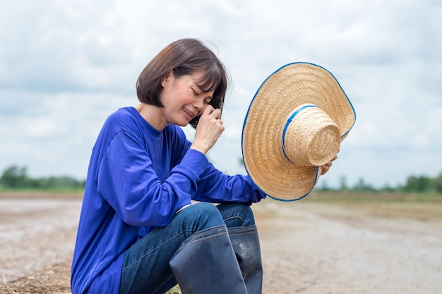 Trauriger asiatischer Bauer, der an Reisfarm sitzt und weint