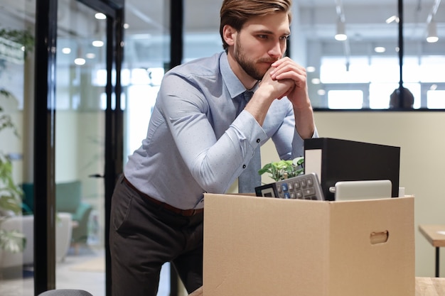 Trauriger entlassener Arbeiter nimmt seine Büromaterialien aus dem Büro mit.