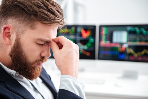 Trauriger erschöpfter junger Geschäftsmann, der Kopfschmerzen im Büro hat