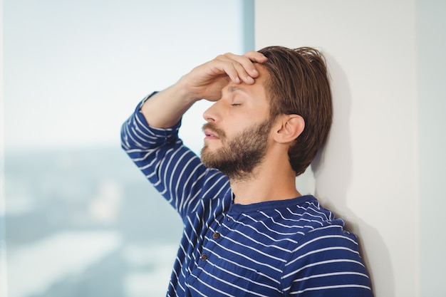 Trauriger Geschäftsmann, der sich an die Wand lehnt