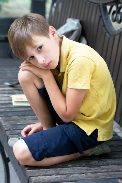 Foto trauriger kleiner junge sitzt auf einer parkbank