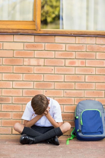 Trauriger Schüler, der alleine im Flur sitzt