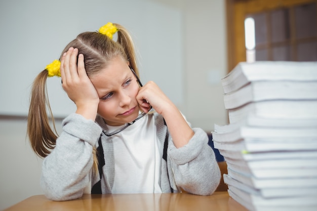 Trauriger Schüler, der an ihrem Schreibtisch in einem Klassenzimmer sitzt