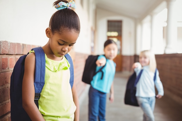 Trauriger Schüler, der von Klassenkameraden am Korridor schikaniert wird