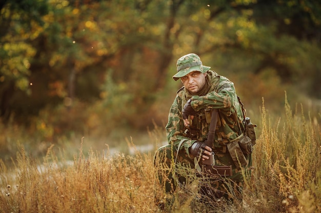 Trauriger Soldat, der mit einer Waffe sitzt