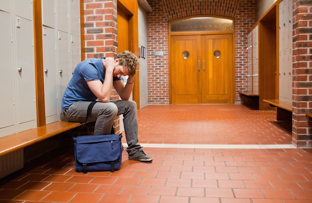 Trauriger Student, der auf einer Bank sitzt