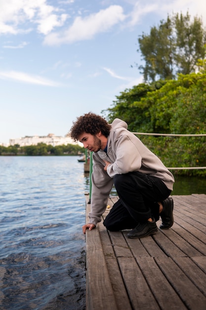 Foto trauriger und nachdenklicher mann, der am see sitzt