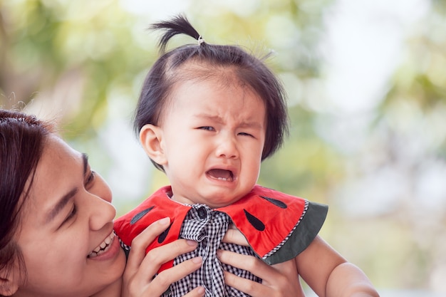 Trauriges asiatisches schreiendes Baby und Mutter, die sie mit Liebe tröstet