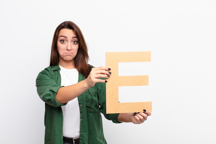 Foto trauriges mädchen, das den buchstaben e des alphabets hält, um ein wort oder einen satz zu bilden