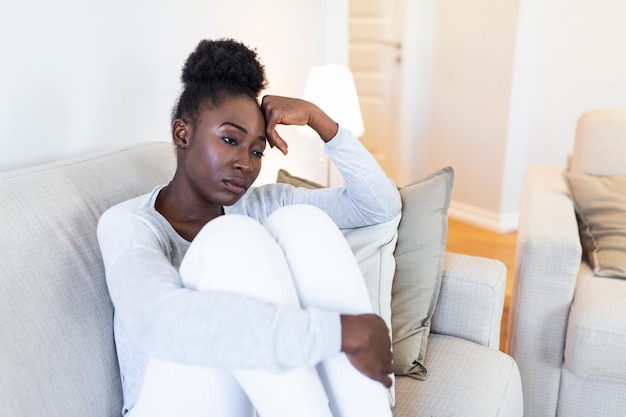 Trauriges, nachdenkliches, besorgtes afroamerikanisches mädchen sitzt auf dem sofa und schaut weg fühlt sich deprimiert, zweifelhaft, einsam, gestresst, verärgert junges schwarzes mädchen denkt an ein psychologisches problem, denkt darüber nach, dass es einen fehler gemacht hat.