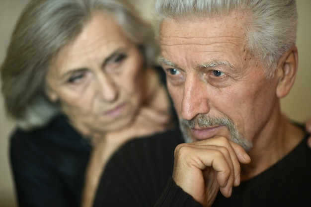 Trauriges reifes Paar in der Nähe der Wand im Zimmer