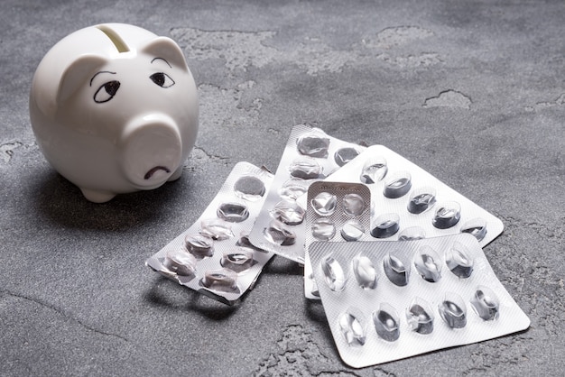 Trauriges Sparschwein, nicht genug Geld für Medical Tablet auf grauer Oberfläche