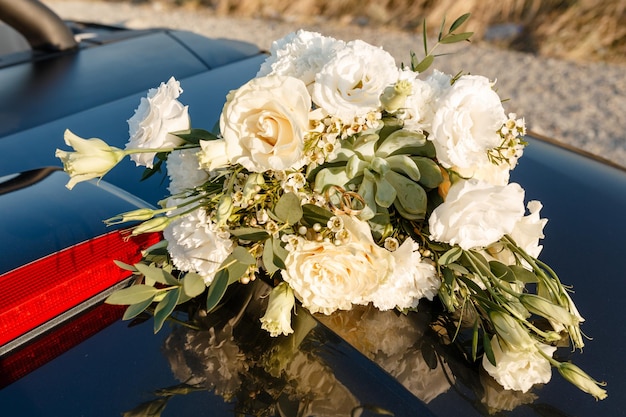 Trauringe liegen als Brautaccessoires auf einem schönen Blumenstrauß