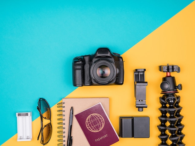 Traveller-Blogger-Kit für den Sommerurlaub. Ansicht von oben. Flach liegen. Kamera mit Zubehör neben Sonnenbrille, Notizbuch und Reisepass