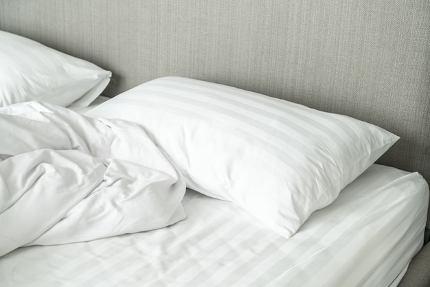 Travesseiro na cama e com cobertor bagunçado de rugas no quarto