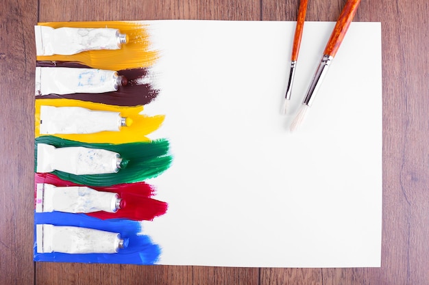 Foto trazos de pintura de colores en la hoja de papel y fondo de mesa de madera