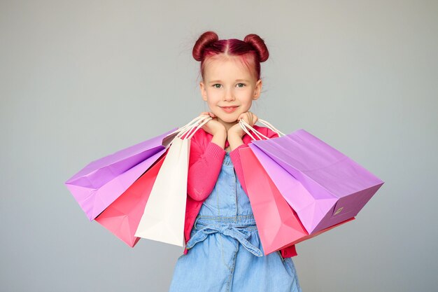 Treffen Sie die Rabatte. Glückliches kleines Baby lächelt mit Papiereinkaufstüten.