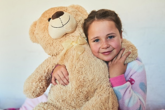 Treffen Sie meinen süßen und kuscheligen Freund Porträt eines süßen kleinen Mädchens, das einen Teddybären umarmt