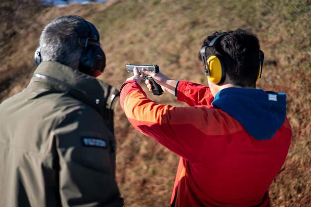 Foto treinador ajudando jovem a mirar com revólver em foto de alta qualidade de treinamento de combate