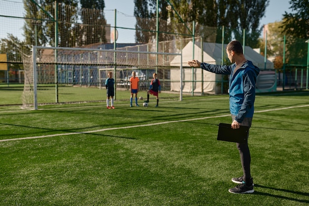 Foto treinador dando instruções aos jogadores do time de futebol infantil durante o treinamento