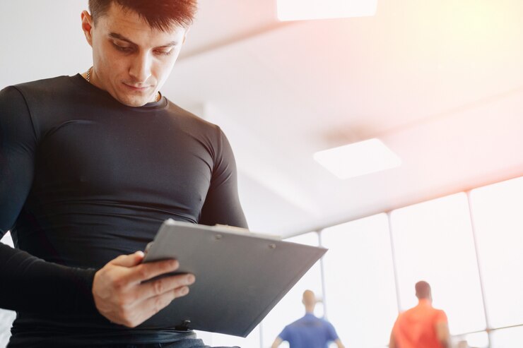 Treinador de cara jovem toma notas no ginásio. personal trainer para esportes.
