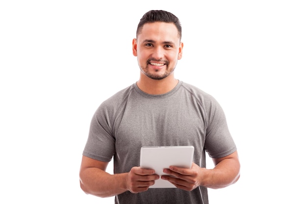 Treinador de fitness jovem atraente usando um computador tablet em um fundo branco