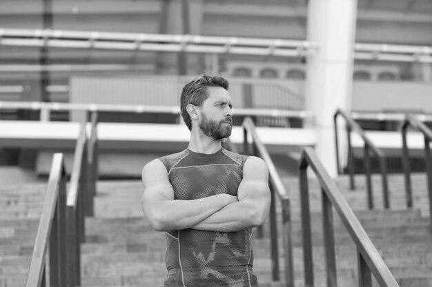 Treinador de fitness muscular homem esperando no fundo da entrada do estádio de escadas