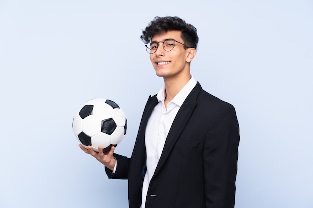 Treinador de futebol argentino sobre parede azul isolada, sorrindo muito