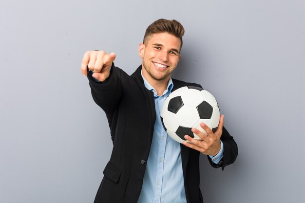 Treinador de futebol jovem alegre sorrisos apontando para a frente.