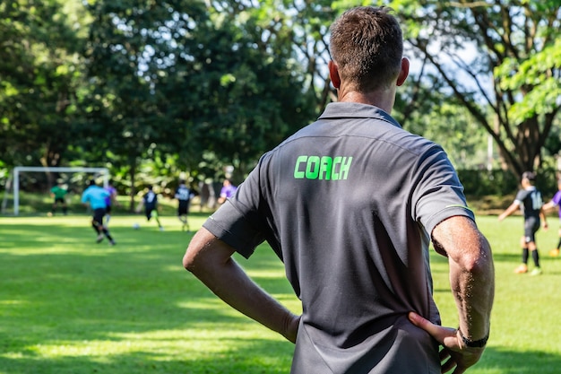 Treinador de futebol ou futebol masculino assistindo sua equipe jogar em um campo de futebol bonito