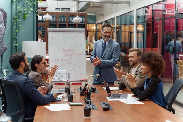 Foto treinador de negócios maduro ou palestrante faz apresentação de flip chart para diversos empresários na reunião