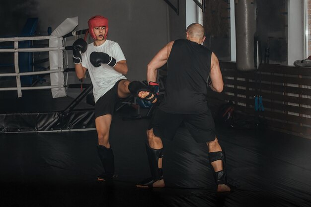 Foto treinador e boxeador adolescente fazendo um treino no ginásio