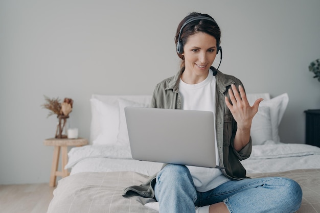 Treinador feminino no fone de ouvido realiza webinar de consulta on-line por videochamada no laptop em casa