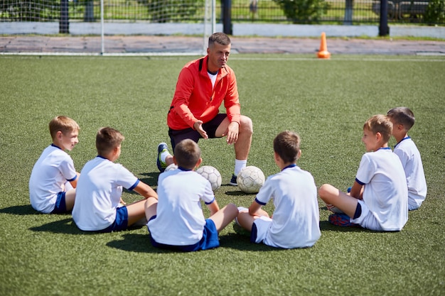 Treinador, instruindo o time de futebol júnior na prática