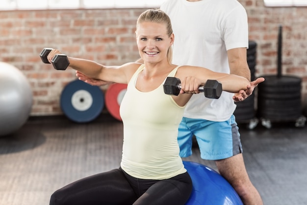 Treinador masculino ajudando mulher jovem com os halteres