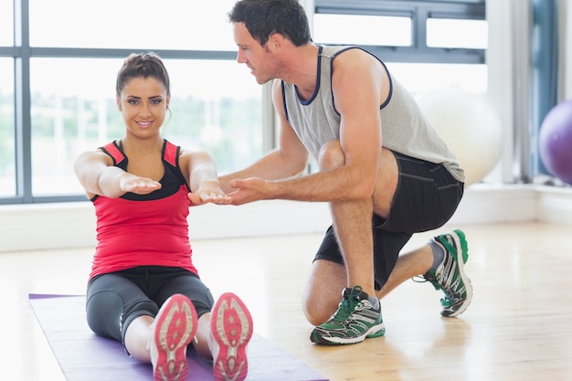 Treinador masculino assistindo mulher com exercícios de pilates no estúdio de ginástica