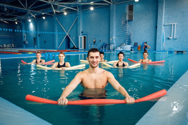 Treinador masculino e grupo feminino, hidroginástica na piscina