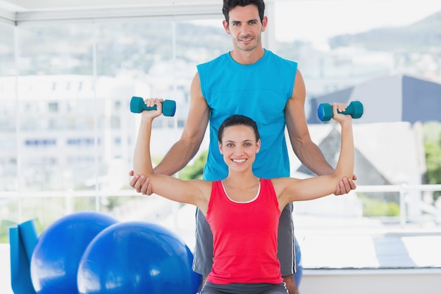 Treinador masculino que ajuda mulher com seus exercícios na academia