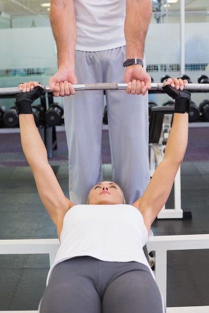 Treinador que ajuda mulher com levantamento de barbell na academia