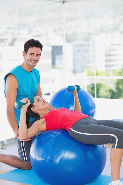 Treinador que ajuda mulher com seus exercícios na academia