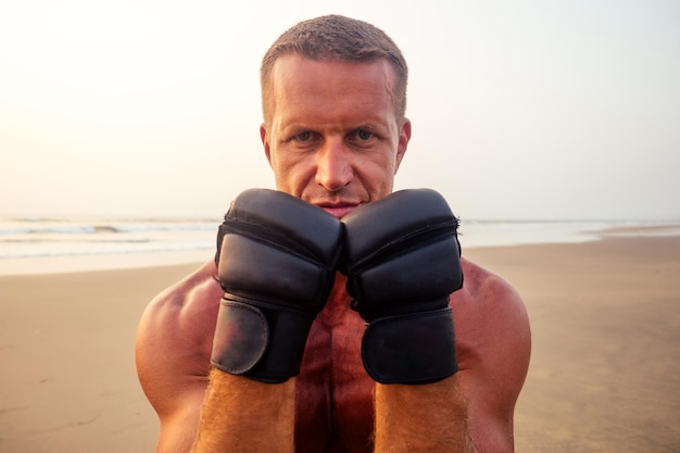 Treinador sem camisa boxer forte durante o exercício de kickboxing com treinador em luvas de boxe no pôr do sol figura motivação perfeita dos músculos abdominais